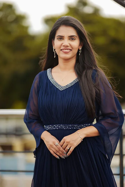 The Pleated Gown in navy, worn outdoors: a V neck edged in silver beadwork, finely pleated georgette through the bodice and a beaded belt at the waist